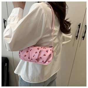 Detail of pink shoulder bag featuring red cherry print and pleated side craftsmanship