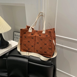 Caramel corduroy tote bag with black bow prints and adjustable canvas straps in a home setting