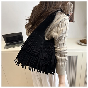 Dettaglio della borsa a spalla in finta pelle scamosciata nera con frange boho