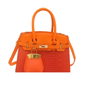 Luxury orange crocodile pattern handbag with gold clasp and mini charm accessory