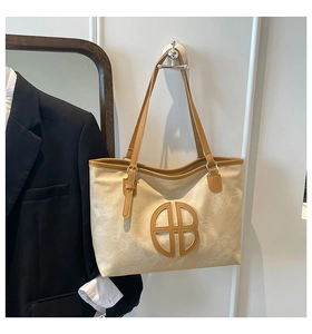 Detail view of large tote bag with contrast piping and metal letter B logo