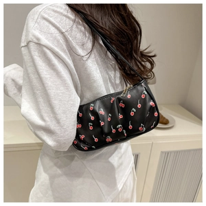 Close-up of trendy black cherry print underarm bag worn by a model in a bright setting