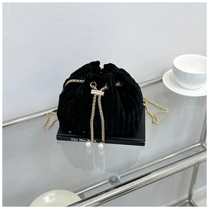 Detail of black corduroy bucket bag with gold chain and elegant pearl drawstring accents