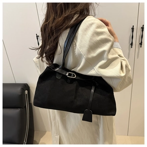 Détail d'un grand sac cabas noir en daim avec boucle métallique et bandoulière longue