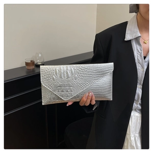 Pochette a busta argento con trama a coccodrillo portata da una modella in stile moderno