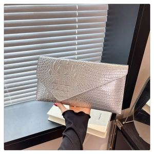 Dettaglio della pochette a busta argento con trama lussuosa in pelle di coccodrillo goffrata