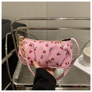 Close-up of pink hobo bag with red cherry prints and golden metal chain detail