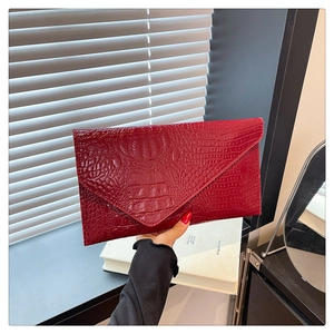 Dettaglio della pelle di coccodrillo lucida bordeaux su una elegante borsa a busta donna