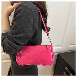 Macro detail of glossy magenta patent leather texture and silver buckle on baguette bag