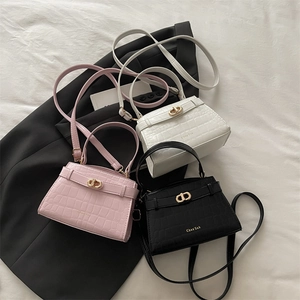 Three crocodile pattern handbags in black, pink, and white with gold locks and top handles