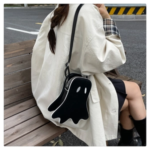 Ghost shaped crossbody bag in black leather worn by a model in an urban outdoor setting