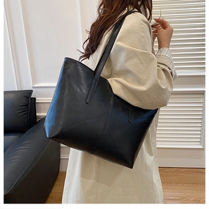 Classic black wax leather tote bag shown with an elegant beige trench coat for office style