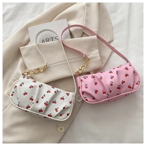 Detail showing white and pink ruched shoulder bags with cherry prints and gold chains