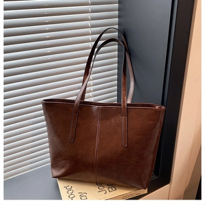 Detail view of large dark brown oil-wax leather tote bag with long handles and retro texture
