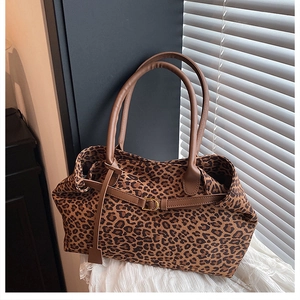 Detail of leopard print tote bag featuring metallic buckle and brown leather handle
