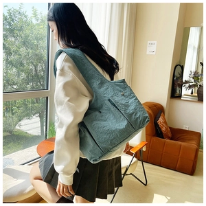 Detail of grey-blue pleated tote bag featuring two front snap pockets and nylon texture