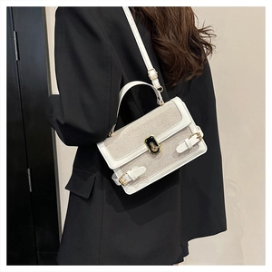 Detail of light beige patchwork handbag with gold clasp and textured fabric finish