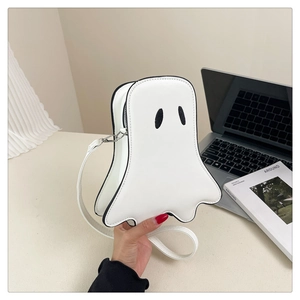 Hand holding white ghost-shaped crossbody bag made of PU leather with black eye detail