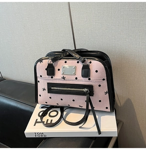 Detail of pink polka dot handbag with black bow embroidery and leather trim finish