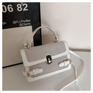 Detailed macro view showing the beige woven texture and gold buckle of this white handbag