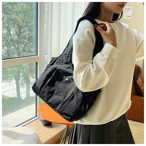 Close-up of black pleated tote bag showing durable textured fabric and side pocket detail