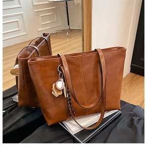 Detail of vintage brown tote bag with baseball charm and contrast stitching accents