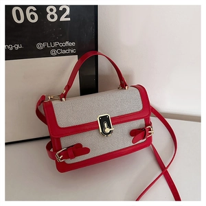 Detail view of woven bag with red leather trim and gold metal lock on cafe background