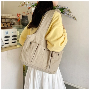Detail view of khaki large capacity multi-pocket tote bag worn on shoulder by model