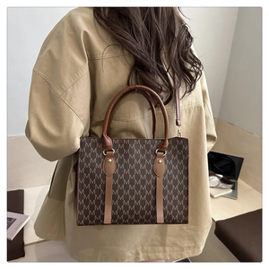 Detail of vintage monogram tote bag styled with a khaki trench coat in office setting