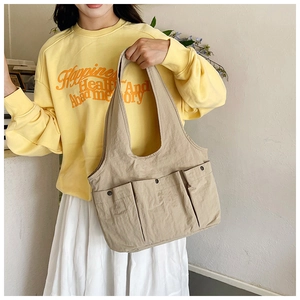 Detail of khaki tote bag with three front snap pockets and comfortable wide shoulder strap