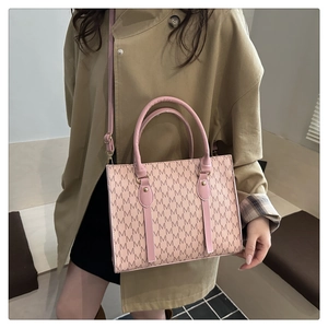 Detailed view of the pink and beige tote bag with M-letter pattern and leather handles