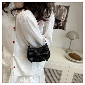Detail of black bow-shaped PU leather handbag with elegant white pearl handle