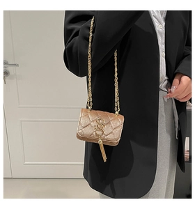 Détail du sac à bandoulière en velours avec chaîne dorée et pompon en métal en intérieur
