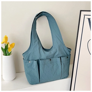 Close-up of pleated blue tote bag with three functional pockets and copper snap buttons