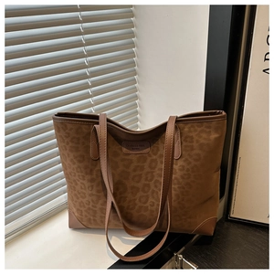 Detail of the leopard print faux suede tote bag featuring a brand logo and dual shoulder straps