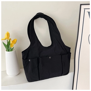 Detail of black pleated tote bag with three external pockets and silver metal snaps