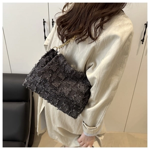 Detail of dark grey tweed crossbody bag featuring rich fringe textures and golden chain