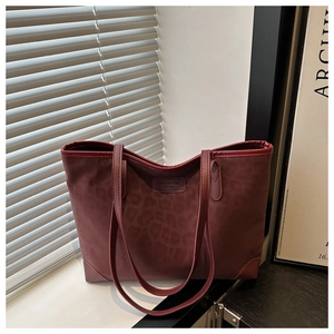 Detail of burgundy faux suede tote bag featuring subtle leopard print and brand patch