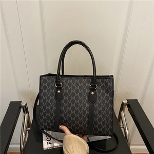 Vintage black tote bag with letter print pattern and golden hardware on office chair
