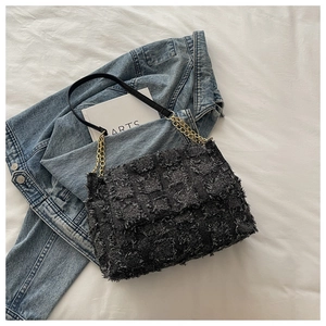 Gros plan sur le sac bandoulière en tweed noir avec texture effilochée et chaîne dorée