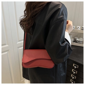 Detail der roten Mini-Tasche aus Saffiano-Leder mit geschwungener Klappe am Model