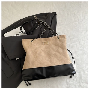 Detail of quilted suede tote with gold hardware and chain strap on a blazer background