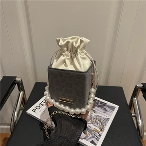 Grey leopard print bucket bag with drawstring closure and large pearl handle strap