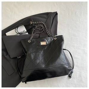 Close-up of black quilted suede bag with gold chain strap and metallic detail