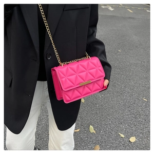 Close-up of bright pink quilted crossbody bag with gold chain strap and metal buckle