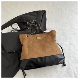 Close-up of diamond quilted brown suede and black leather panels with gold hardware