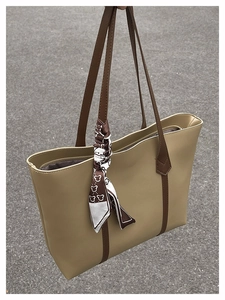 Detail of beige tote bag with dark brown handles and decorative patterned silk scarf