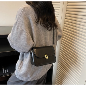 Detail view of a black vintage crossbody bag with a gold twist lock and fine stitching