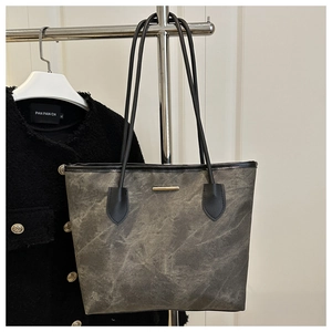 Detail of grey textured tote bag hanging on a rack with golden metal hardware accent