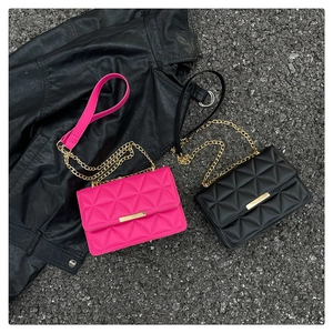 Detail of rose red and black quilted chain crossbody bags on a leather background
